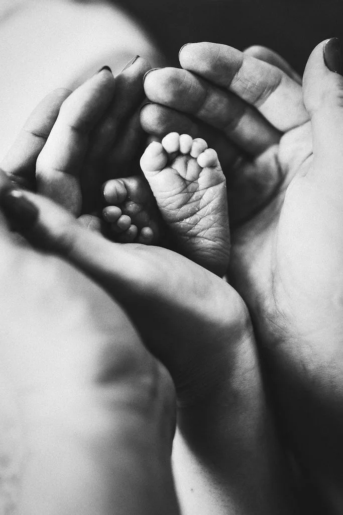 Babyfüße geborgen in den Händen der Eltern, Schwarz-Weiß