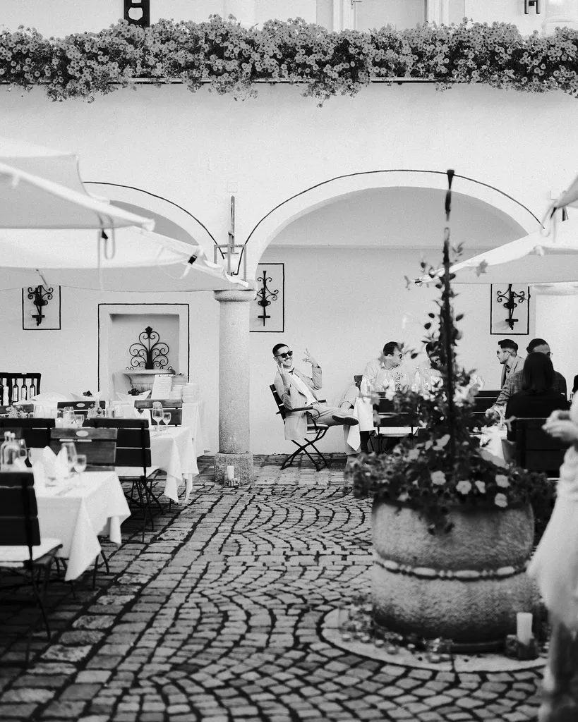 Hochzeitsfeier im gepflasterten Innenhof mit Arkaden und Blumenschmuck, Schwarz-Weiß