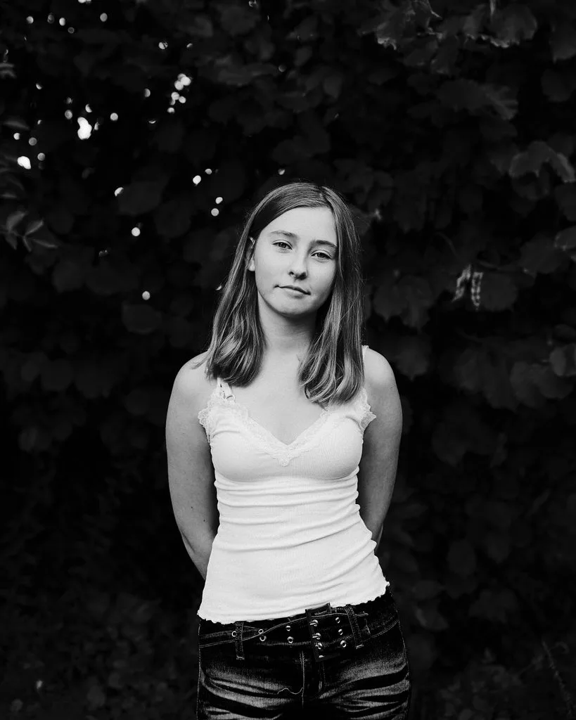 Portrait einer Jugendlichen vor dunklem Laub, Schwarz-Weiß