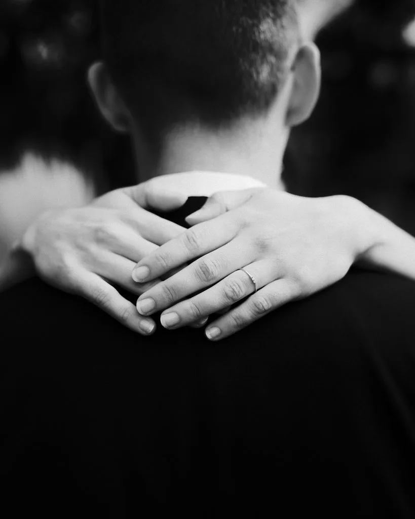 Hände der Braut mit Ehering auf den Schultern des Bräutigams, Schwarz-Weiß