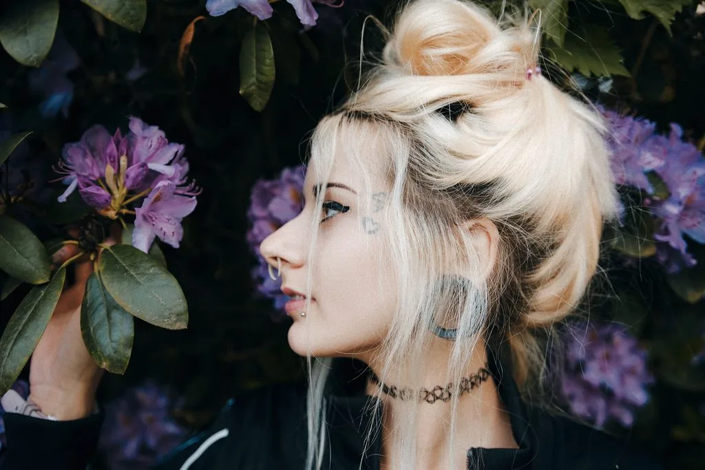 Profilportrait einer blonden Frau vor lila Rhododendronblüten
