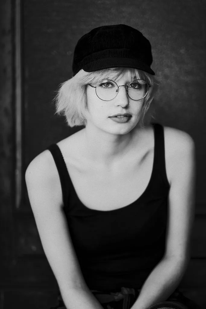 Portrait einer jungen Frau mit Brille und Schiebermütze, Schwarz-Weiß