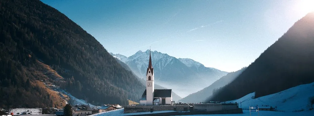 Winterliches Luttach in Südtirol: Kirchturm vor verschneiten Bergen