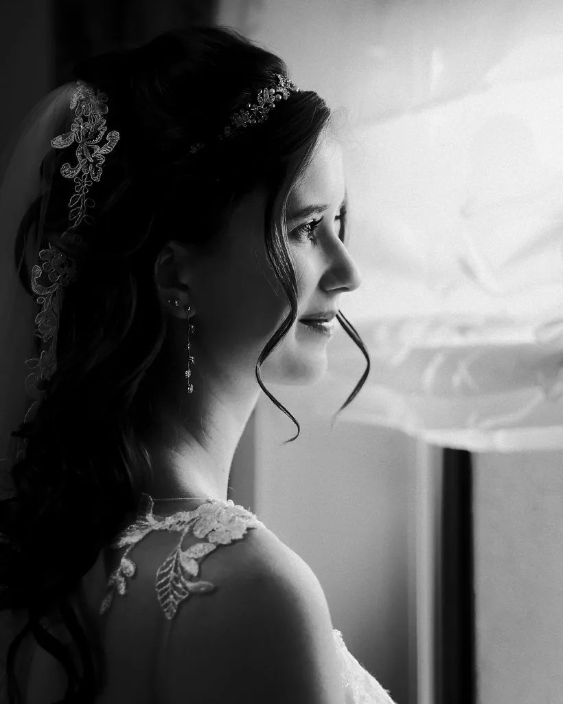 Braut mit Haarschmuck und Schleier im Profil am Fenster, Schwarz-Weiß-Portrait